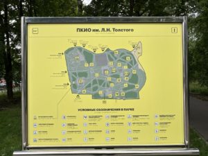 На фотографии крупным планом запечатлен установленный на улице информационный стенд с желтой картой-схемой «ПКиО им. Л.Н. Толстого», под которой расположена подробная текстовая схема с условными обозначениями объектов парка.