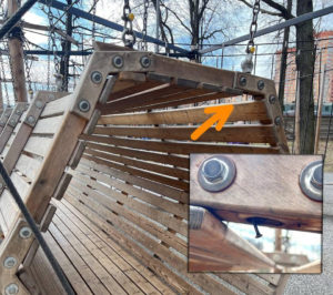 На фотографии запечатлены подвесные деревянные качели-кокон, на верхнюю балку которых указывает оранжевая стрелка, а на увеличенной вставке снизу крупным планом показан опасно торчащий из древесины острый саморез.