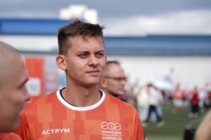 На фото Артур Сайфутдинов. Он одет в оранжевую  футболку и смотрит вдаль